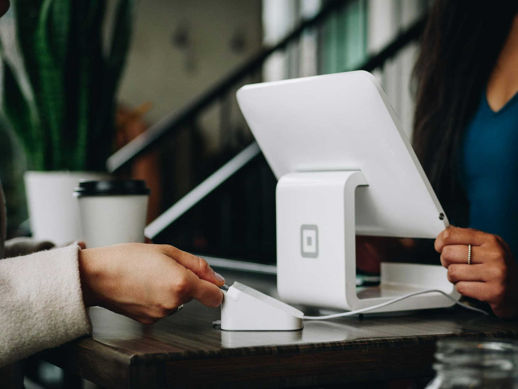 A small-business owner taking a card payment at their shop counter